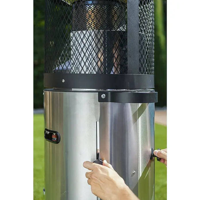 Enders Estufa de exterior Polo - 3 kW - 6 kW, Altura: 115 cm - Primer plano de una persona ajustando un mando en un elegante calentador de patio plateado al aire libre, para un ambiente cálido.