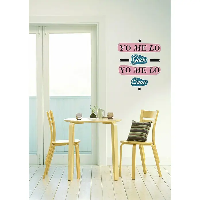 Vinilo de pared Yo me lo como - Multicolor, Plástico - Acogedor comedor con una mesa redonda de madera, dos sillas y elementos decorativos en la pared para un ambiente acogedor.