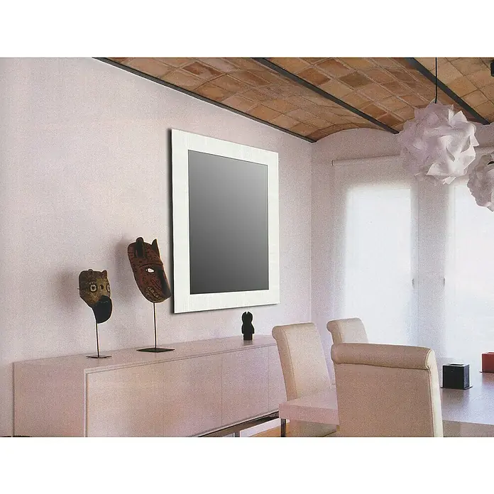 Espejo de pared Riga - 64 x 86 cm, Blanco - Interior de una habitación con un espejo moderno colgado sobre un aparador adornado con máscaras y decoraciones. El interior es luminoso y elegante.