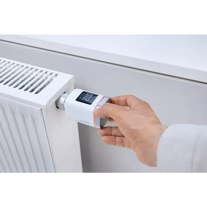 Bosch Smart Home Heizkörper-Thermostat II - M30 x 1,5 mm - Ein Bosch Heizkörperthermostat wird von einer Hand bedient, um die Raumtemperatur zu regulieren und Energie zu sparen.