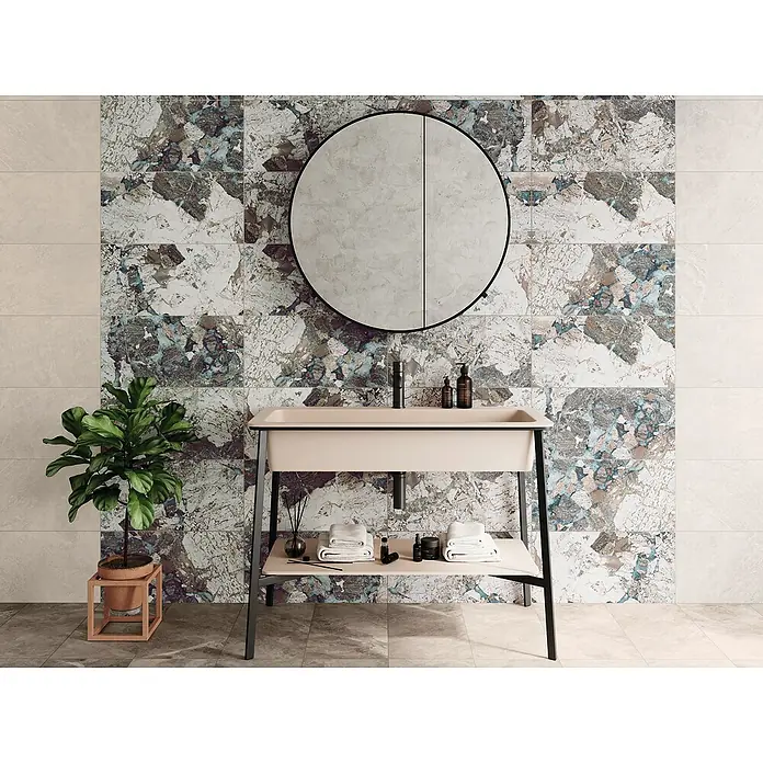 Domicil Wandfliese Stone Art Landscape - 30 x 60 cm, Blau/Grau/Beige, Glänzend - Badezimmerwaschtisch mit modernem Design und Marmorfliesen im Hintergrund, ergänzt durch einen runden Spiegel und dekorative Accessoires.