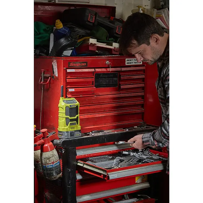 Ryobi ONE+ Radio Bluetooth de batería R18R-0 - Frecuencia: 87,5 - 108,0 kHz (FM) - Escena de taller con un cofre de herramientas rojo Snap-on lleno de herramientas y flanqueado por una radio Ryobi y un limpiador de frenos.
