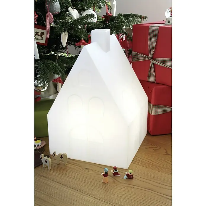 8 Seasons Design Shining LED-Solar-Dekoleuchte House - 2 W, Weiß, L x B x H: 39 x 39 x 57 cm - Weihnachtliche Szene mit leuchtendem Haus, Geschenken und Weihnachtsbaum. Das Haus ist im Fokus, umgeben von festlicher Dekoration.
