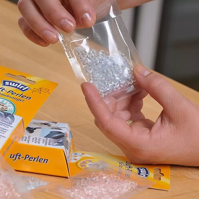 Swirl Staubsauger-Duftperlen - Aloe, 4 Stk. - Eine Person hält einen Beutel mit transparenten Duft-Perlen für Staubsauger; Produktverpackung ist sichtbar.