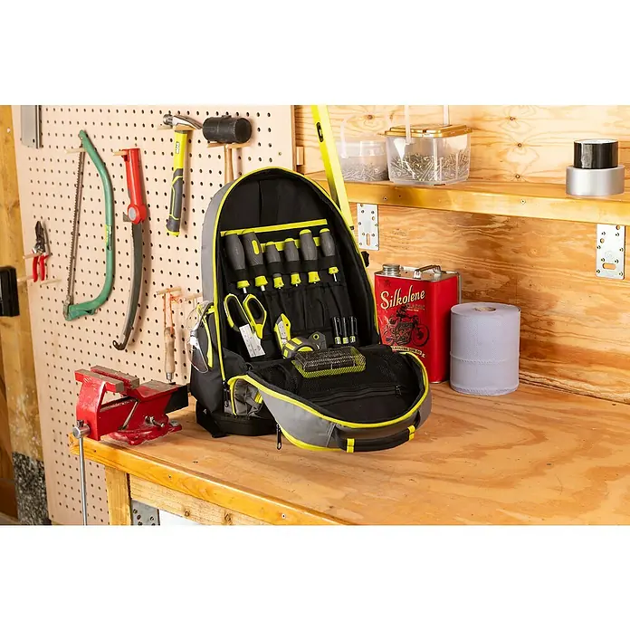 Ryobi Werkzeugrucksack RSSBP1 - 20 l, Grün/Schwarz - Werkzeugrucksack mit Werkzeugen auf einer Werkbank, umgeben von anderen Werkzeugen.