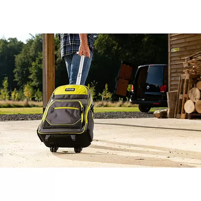 Ryobi Werkzeugrucksack RSSBP2 - 20 l, Ausstattung: Räder - Eine Person zieht eine gelb-graue RYOBI Rollwerkzeugtasche auf befestigtem Untergrund mit ausziehbarem weißem Griff.