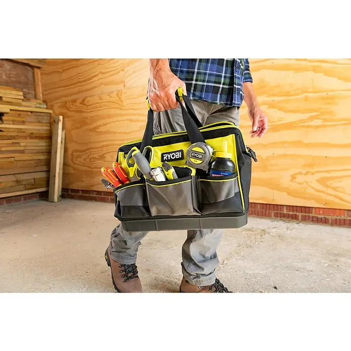 Ryobi Werkzeugtasche RSSSTB1 S - Polyester, Größe: S - Ein Ryobi Werkzeugkoffer, gefüllt mit diversen Werkzeugen, wird von einer Person in Arbeitskleidung getragen.