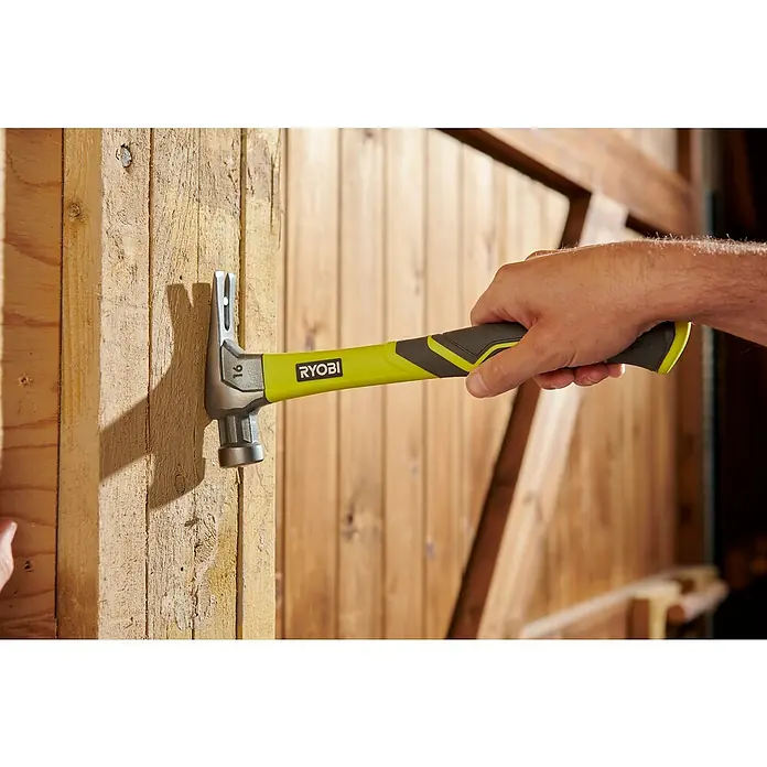 Ryobi Klauenhammer RH16FSSGewicht Kopf: 450 g, Stahl - Nahaufnahme eines Ryobi-Hammers, der zum Einschlagen eines Nagels in ein Holzstück verwendet wird.