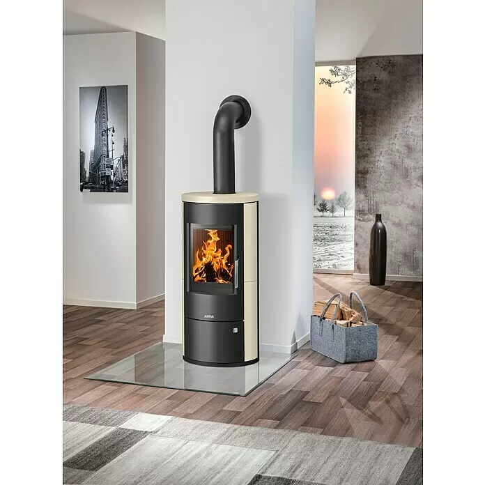 Justus Kaminofen Austin 7 - 7 kW, Raumheizvermögen: 144 m³, Material Verkleidung: Kalkstein, Cream/Schwarz - Ein moderner schwarz-beiger Kaminofen mit Glasfront und sichtbaren Flammen, auf einer Glasplatte im Wohnzimmer.