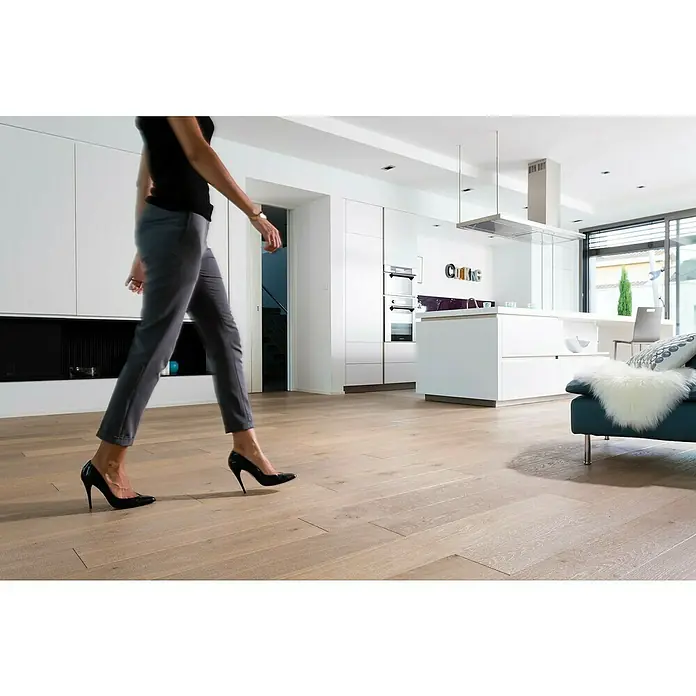 V33 Barniz para parquet Ultra resistente - Incoloro, Mate, 2,5 l - Elegantes pantalones grises y tacones altos negros sobre un pavimento de madera clara, complementando el diseño interior moderno.