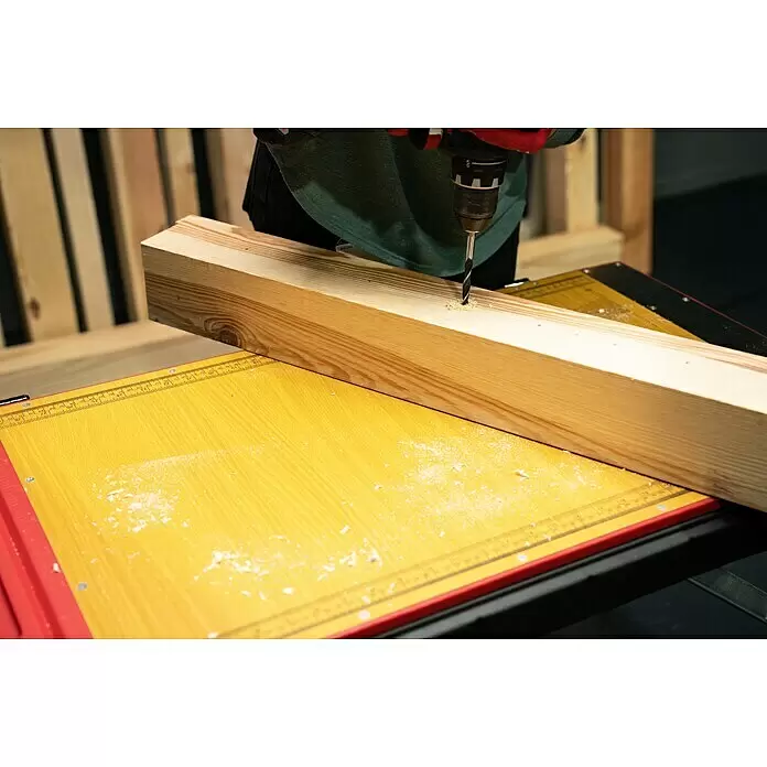 Werkbank Tragbar Duplex - L x B: 1.360 x 790 mm, Arbeitshöhe: 840 mm, Belastbarkeit: 150 kg - Nahaufnahme eines Bohrers, der ein Loch in einen hellen Holzbalken bohrt; Späne auf gelbem Untergrund.