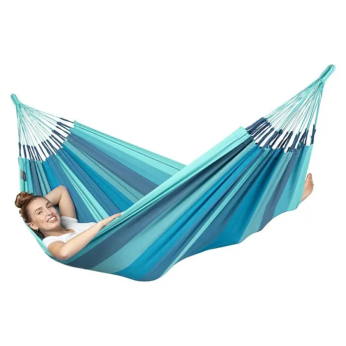 La Siesta Hängematte Modesta - L x B: 300 x 140 cm, Lagoon, Single - Frau entspannt in einer blau gestreiften Hängematte. Die Hängematte ist ideal für den Garten, die Terrasse oder den Balkon.
