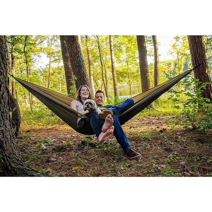 La Siesta Hängematte Colibri 3.0 - L x B: 270 x 170 cm, Canyon, Single - Ein Paar entspannt in einer Hängematte im Wald mit einem niedlichen Hund, die Hängematte ist der perfekte Ort zum Entspannen.