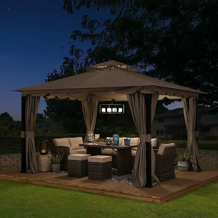 Sunjoy Pavillon Stoj - B x T: 402 x 336 cm, Farbe Gestell: Schwarz, Stahl - Das Bild zeigt einen Pavillon mit Vorhängen, der auf einer Holzterrasse steht und mit Möbeln und einer Lampe ausgestattet ist.