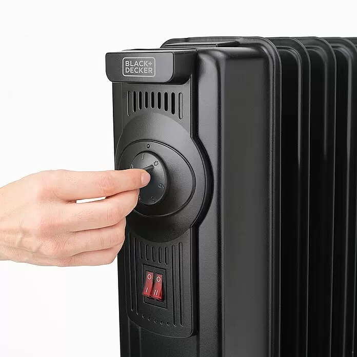 Black+Decker Ölradiator BXRA2300E - 2.300 W, Raumgröße bis ca. 23 m², Schwarz - Schwarzer Ölradiator mit einer Hand, die den Thermostatknopf und sichtbare Netzschalter einstellt.