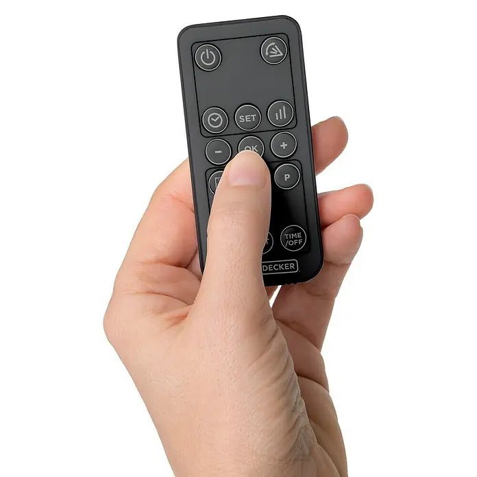 Black+Decker Heizlüfter BXWSH2000E - 1.000 W - 2.000 W, Anthrazit, IPX2 - Nahaufnahme einer Hand, die eine schwarze Black+Decker-Fernbedienung hält und die "OK"-Taste drückt, isoliert auf Weiß.