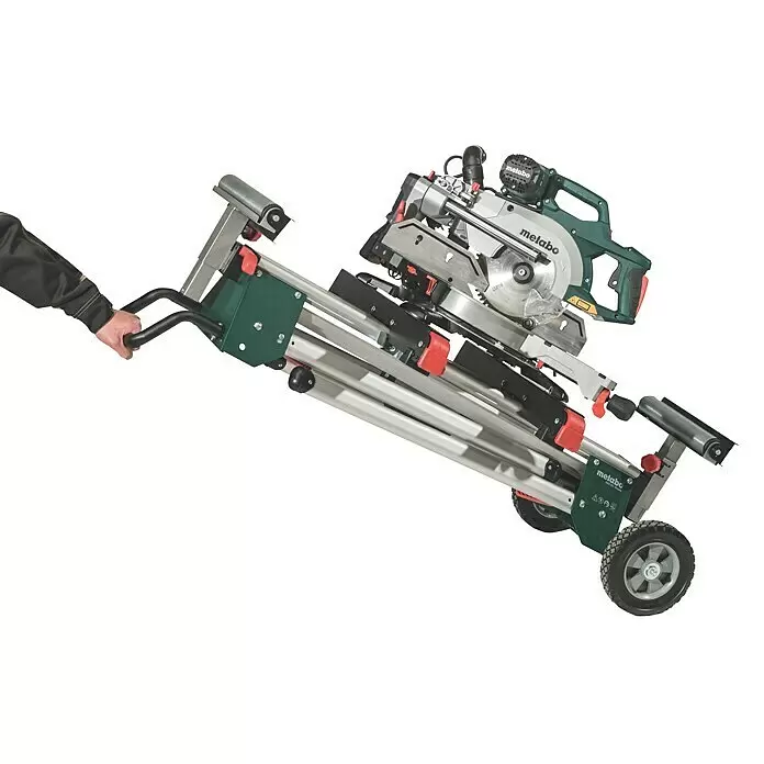 Metabo Sägetisch KSU 251 - Geeignet für: Kappsägen, Traglast: 250 kg - Eine Person zieht eine Metabo Gehrungssäge auf einem grau-grünen mobilen Untergestell mit Rädern.