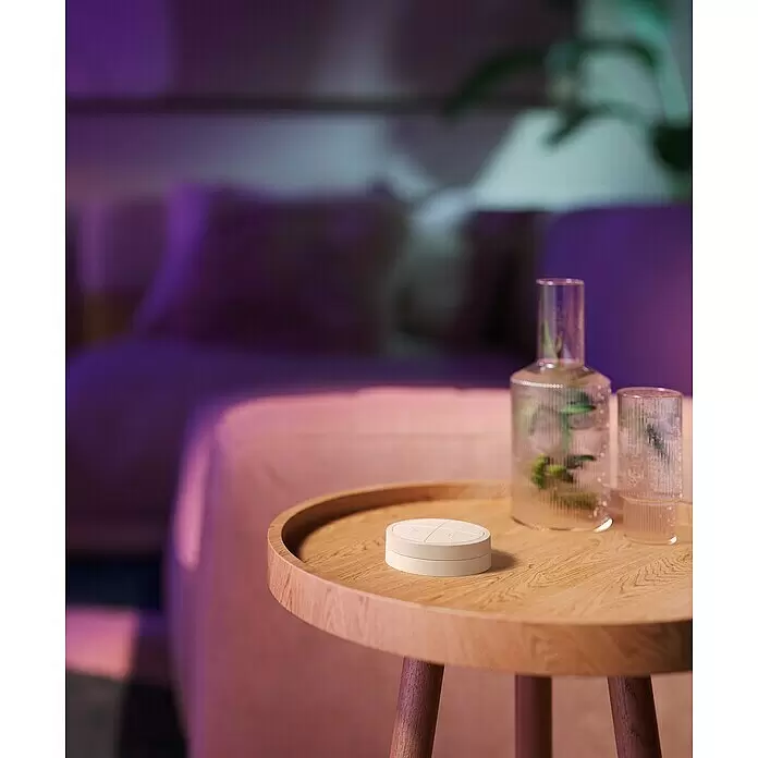 Philips Hue Lichtsteuerung Tap Dialswitch - 6 x 6 x 2 cm, Smart Home-fähig: Ja, Weiß, Dimmbar - Weißes Smart-Home-Bedienelement auf Holztisch in einem Raum mit stimmungsvoller Beleuchtung.