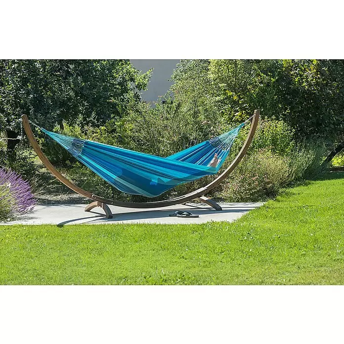 La Siesta Hängematte Modesta - L x B: 350 x 160 cm, Lagoon, Double - Gestreifte blaue Hängematte auf Holzständer im Garten, mit Füßen darin und Flip-Flops daneben.