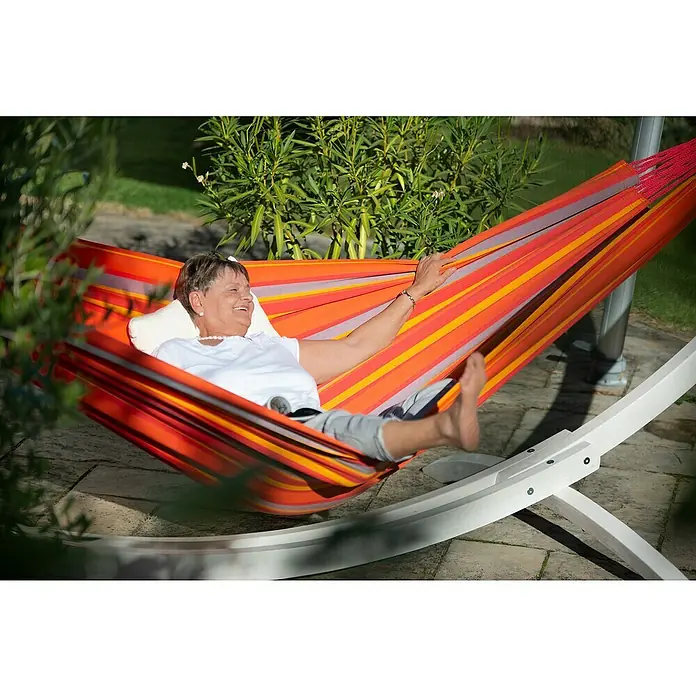 La Siesta Hängematte Brisa Kingsize - L x B: 400 x 180 cm, Toucan - Entspannung pur: Frau genießt die Sonne in einer farbenfrohen Hängematte im Garten, die zum Verweilen einlädt.
