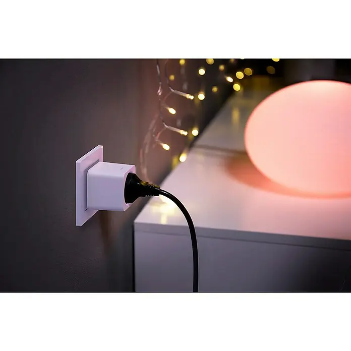 Philips Hue Smart-LED-Lampen Set White & Color AmbianceE27, Dimmbar, Warmweiß, 806 lm - 1.055 lm, 9 W - Ein intelligenter Stecker ist in eine Steckdose gesteckt, mit einer schwarzen Schnur, die zu einem runden, rosa beleuchteten Gerät führt.