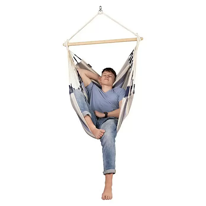 La Siesta Hamaca colgante Domingo Basic - L x An x Al: 140 x 90 x 145 cm, Azul/Blanco - Sillón colgante a rayas con barra de madera, un joven se relaja en él. Tela azul, blanca y gris.