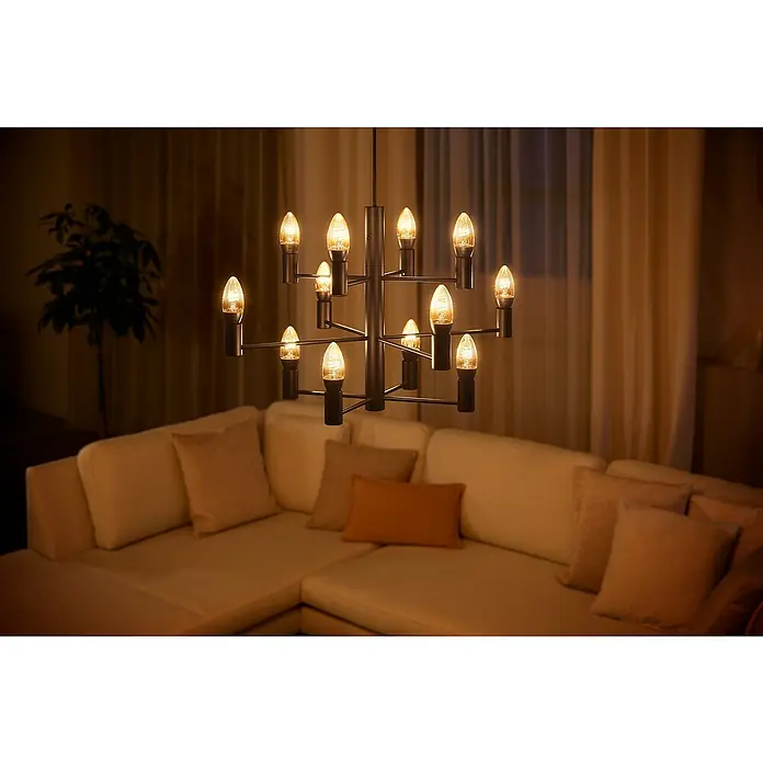 Philips Hue Smart-LED-Lampen Set Smart Vintage E27E14, Dimmbar, Warmweiß, 300 lm, 4,5 W, 1 Stk. - Eine moderne, schwarze Hängeleuchte mit zwölf LED-Kerzenlampen über einer Couch. Das warme Licht sorgt für eine gemütliche Atmosphäre.