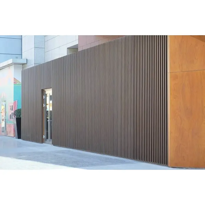 Dioco Revestimiento decorativo alistonado - L x An: 220 x 17 cm, Teka - Primer plano de una fachada moderna con listones verticales de madera y una puerta, que muestra un diseño elegante y funcionalidad.