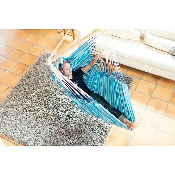 La Siesta Hängesessel Habana Kingsize - L x B x H: 210 x 130 x 170 cm, Azure - Ein Mann entspannt in einer hellblauen Hängematte, die von einem Holzrahmen gehalten wird. Die Hängematte scheint bequem und einladend zu sein.