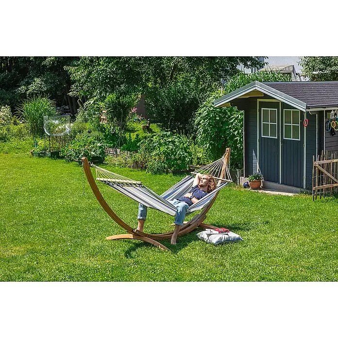 La Siesta Stabhängematte Alisio - L x B: 300 x 140 cm, Sea Salt, Single - Gestreifte Hängematte auf Holzgestell in einem Garten, eine Person entspannt darin. Der Stoff ist blau, weiß und grau.