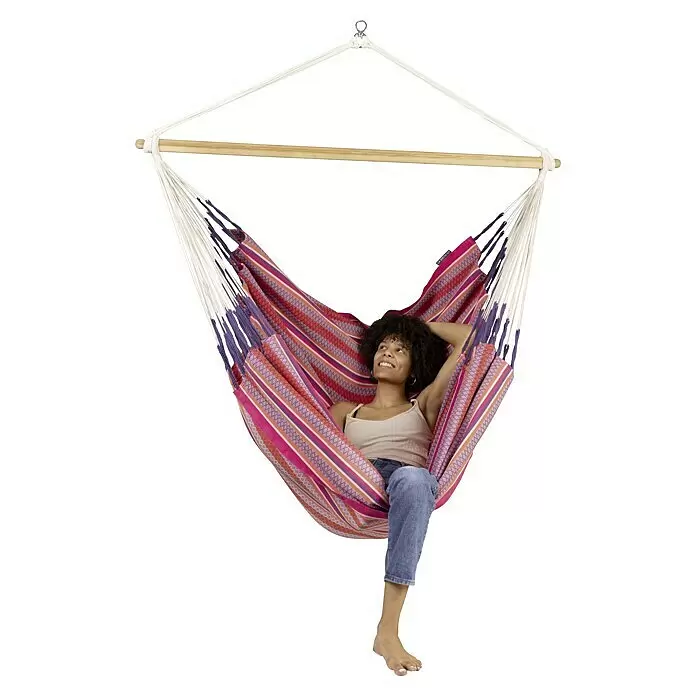La Siesta Hamaca colgante Habana Kingsize - L x An x Al: 210 x 130 x 170 cm, Rojo/Blanco - Silla hamaca de rayas coloridas con barra de extensión de madera, con una mujer relajándose.