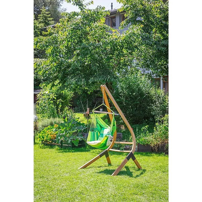 La Siesta Kissenhülle Cariño - Jungle, L x B: 50 x 50 cm, Baumwolle - Grüne Hängesessel-Szene im Garten. Der Sessel hängt an einem Holzgestell und lädt zum Entspannen im Grünen ein.