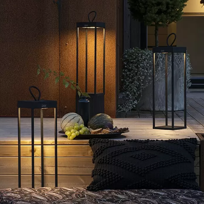 Konstsmide Außenlaterne Ravello -  - Schwarze Außenlaternen mit warmem Licht im modernen Design, die eine Holzterrasse beleuchten.