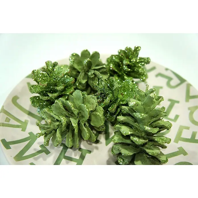 Fleur Purpurina Glitter - Jade Green, 90 g, Brillante - Primer plano de piñas verdes con purpurina sobre un plato con un patrón de letras verdes.