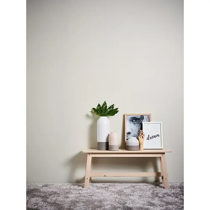 A.S. Création Vliestapete Glatte Wand Meistervlies 5 - Creme, Uni, 10,05 x 0,53 m - Stilvolle Einrichtung mit einer Holzbank, Vasen und einem gerahmten Bild mit der Aufschrift "Dream", die eine moderne Raumatmosphäre schafft.