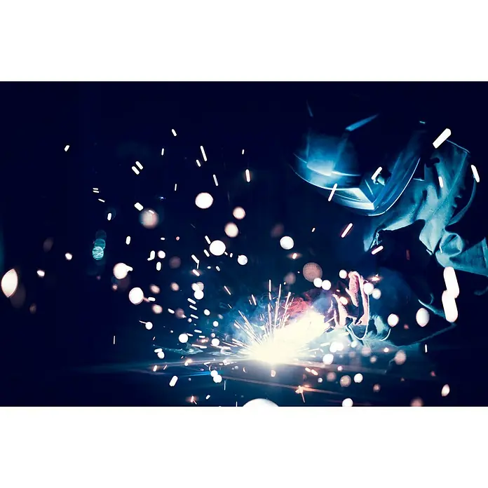Gys Soldador combinado Easymig 150 - Corriente de soldadura: 20 A - 140 A - Primer plano de un soldador con equipo de protección, trabajando entre chispas y uniendo metales.