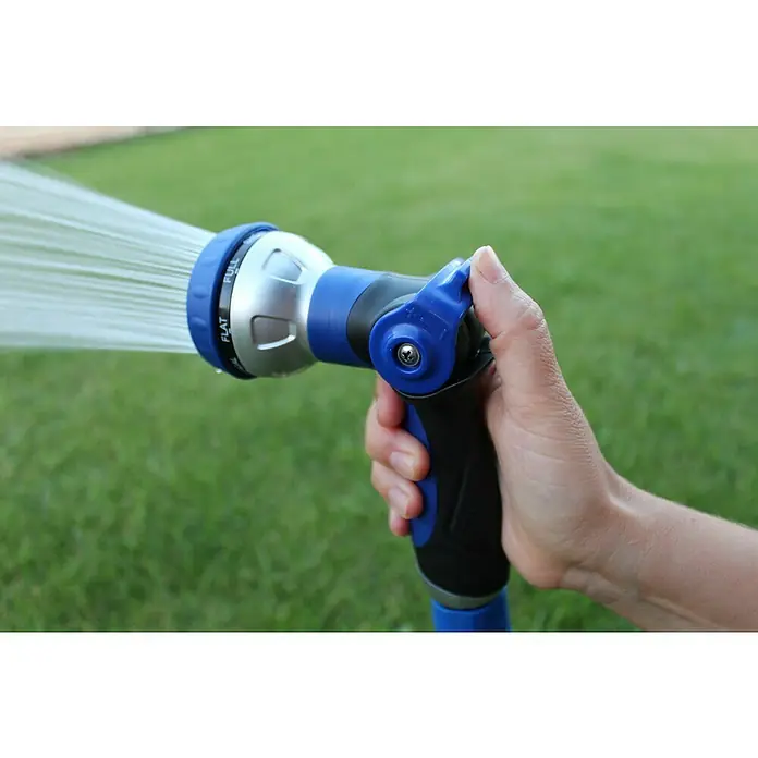 Kit de manguera en espiral Eva - Largo: 15 m, Plástico - Primer plano de una mano sosteniendo una manguera de jardín azul y plateada con una boquilla ajustable que rocía agua sobre césped verde.