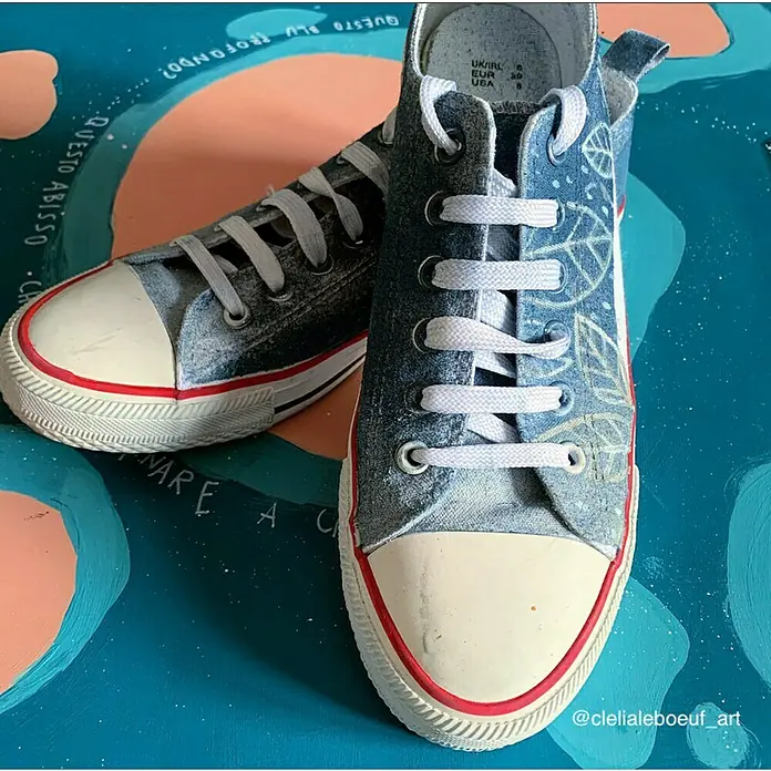Fleur Pintura decorativa en spray Chalky Look - Copenhague Blanco, Mate, 300 ml - Primer plano de dos zapatillas de denim azul con punta blanca y detalles rojos sobre una superficie verde azulada.