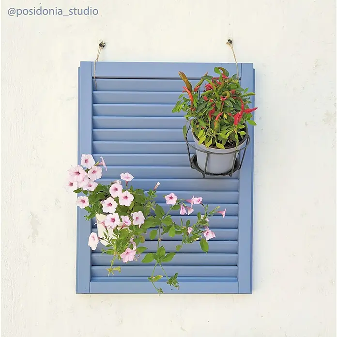 Fleur Pintura decorativa en spray Chalky Look - Smoky, Mate, 300 ml - Una persiana azul sobre una pared blanca, mostrando dos macetas, una con flores rosas y la otra con rojas.