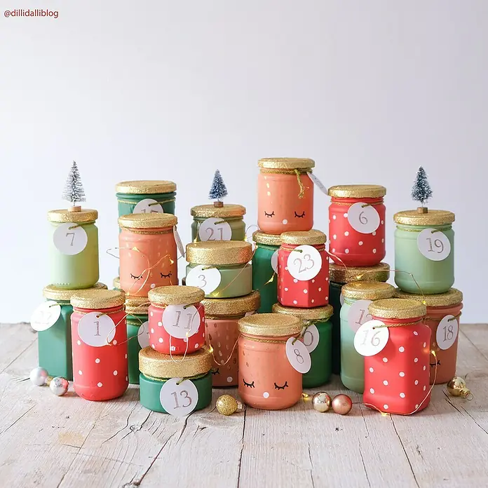 Fleur Pintura decorativa en spray Chalky Look - Tomate Red, Mate, 300 ml - Calendario de adviento hecho de recipientes de vidrio pintados con tapas doradas y números, expuesto sobre una mesa de madera clara.