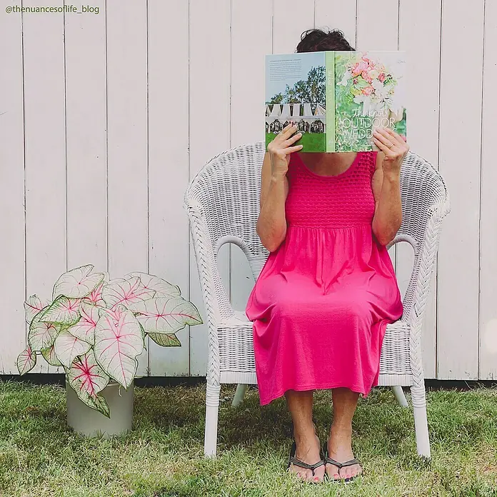 Fleur Pintura decorativa en spray Chalky Look - Titanium Blanco, Mate, 300 ml - Mujer con un vestido rosa sentada en una silla blanca leyendo un libro titulado "The Perfect Outdoor Wedding".