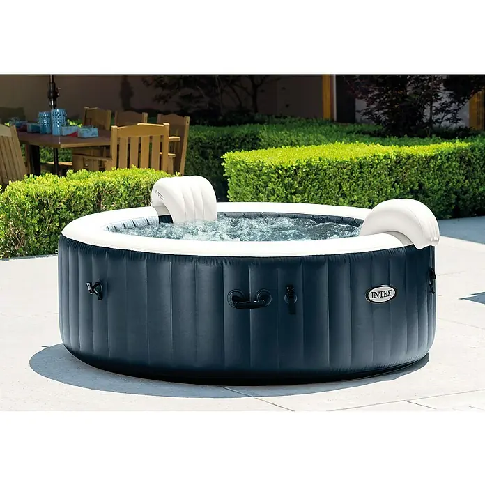 Intex Pure Spa Mobil-Whirlpool 85 Bubble MassageØ x H: 216 x 71 cm, Navy, 1.098 l - Nahaufnahme eines aufblasbaren Intex Whirlpools im Garten. Der Whirlpool ist dunkelblau mit weißem Rand und verfügt über Kopfstützen.