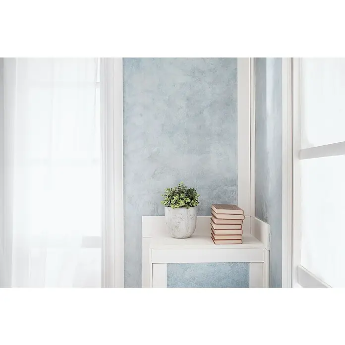 Osaka Yeso con efecto de color Nubia - Plata óxido, Brillante - Libros y una planta se sientan en una mesa auxiliar, creando un ambiente acogedor. El objeto de arte añade un ambiente tranquilo y pacífico a la habitación.