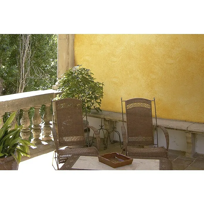 Osaka Yeso con efecto de color CalDur - Beige, Mate - Terraza con dos sillas de mimbre y una mesa con cenicero, detalles de vegetación y una pared amarilla texturizada de fondo.