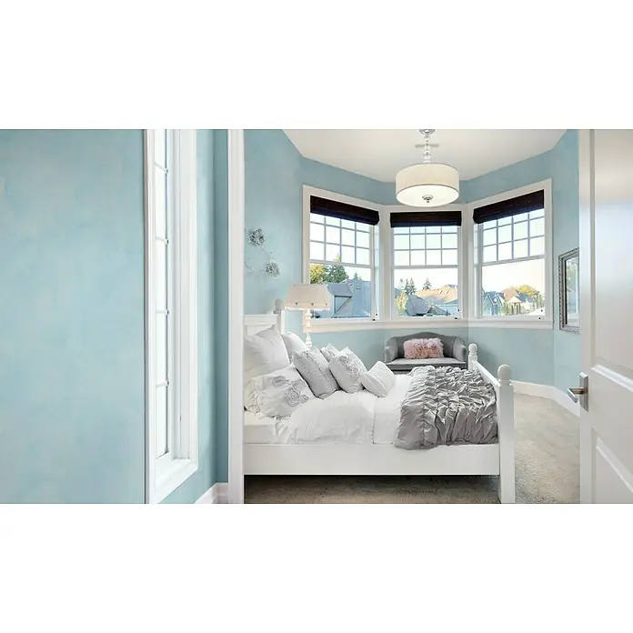 Osaka Yeso con efecto de color CalDur - Beige, Mate - Dormitorio luminoso con cama blanca y paredes azules bajo una luz elegante, que irradia un ambiente relajante y tranquilo.