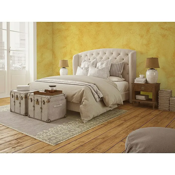Osaka Pintura para efectos decorativos Arena - 5 l, Amarillo, Mate - Un dormitorio elegante con una lujosa cama con penachos, elegantes mesitas de noche y baúles decorativos que crean un ambiente sereno.