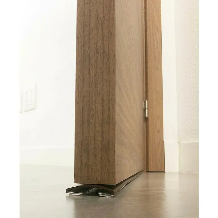 Junta para puerta Antipinzamiento - Marrón, Largo: 1 m - Primer plano de una puerta de madera con un burlete automático, diseñado para el aislamiento acústico y la eficiencia energética.