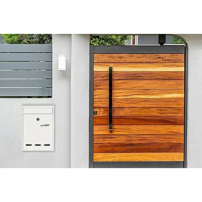 Portaferm Wandbriefkasten PF 11 - L x B x H: 7,5 x 21,5 x 31,5 cm, Weiß, Stahl, Sichtfenster - Eine moderne Briefkastenanlage und ein Holztor. Der Briefkasten ist weiß und das Tor ist aus braunem Holz gefertigt.