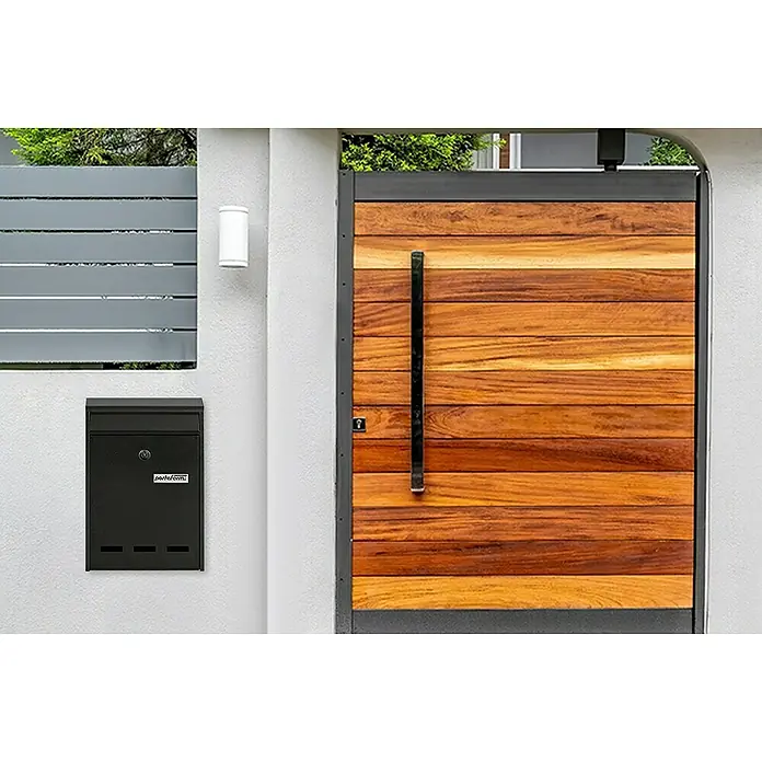 Portaferm Wandbriefkasten PF 11 - L x B x H: 7,5 x 21,5 x 31,5 cm, Grau, Stahl, Sichtfenster - Bild eines schwarzen Briefkastens an einer Wand neben einem Holztor.