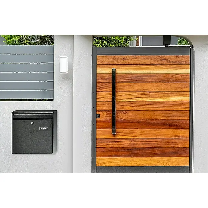Portaferm Wandbriefkasten PF 44 - L x B x H: 10 x 36,2 x 32,2 cm, Grau, Stahl - Eine moderne schwarze Metall-Briefkastenanlage an einer grauen Betonmauer, neben einer Holztür und einer Wandlampe.